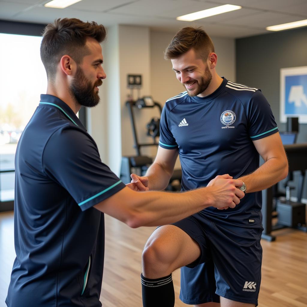 Football player working with a physiotherapist during knee rehabilitation exercises